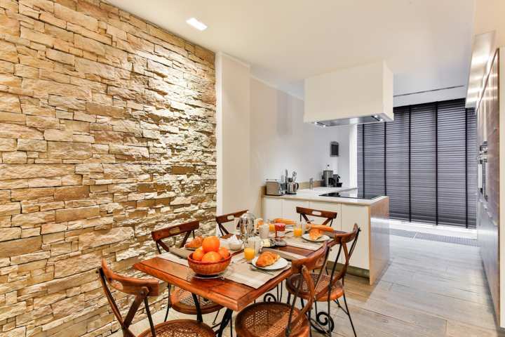 Cocina de colores cálidos, con mesa y sillas marrones Arquitectura e interiorismo Barcino Construcciones