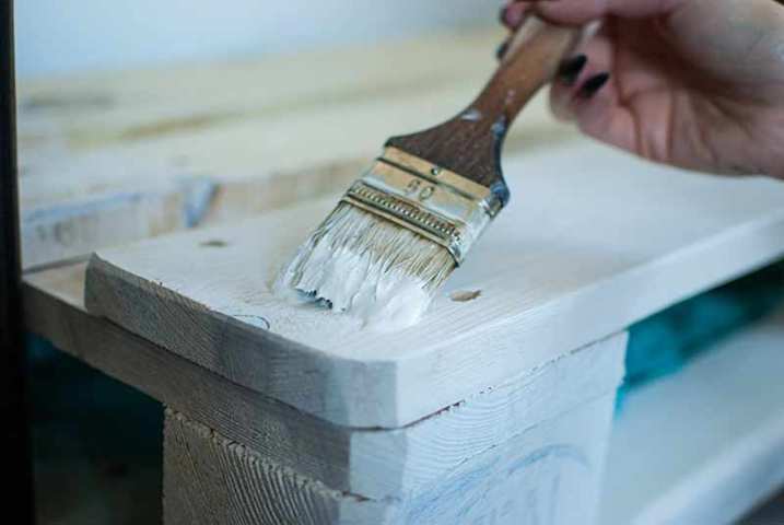 Trabajos de pintura en tablones de madera Mano con pincel y pintura blanca