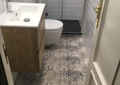 Baño reformado mueble de baño con lavabo grifos suelo rústico ducha y puerta de entrada